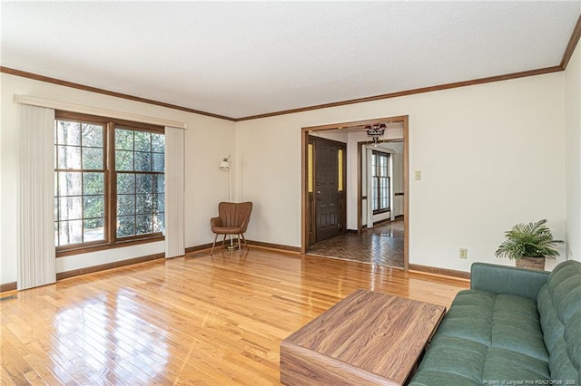 living area featuring baseboards, visible vents, ornamental molding, and wood finished floors