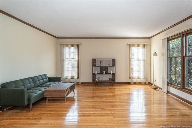 living area with ornamental molding, light wood-type flooring, and baseboards