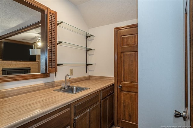 kitchen with lofted ceiling, light countertops, a sink, and a textured ceiling