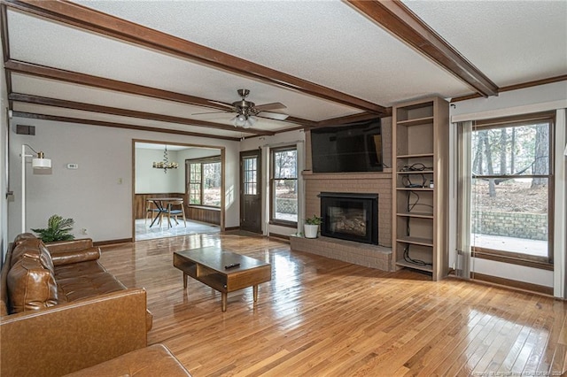 living area with a textured ceiling, light wood-type flooring, a fireplace, and beam ceiling