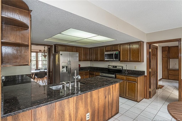 kitchen with appliances with stainless steel finishes, a peninsula, open shelves, a sink, and light tile patterned flooring