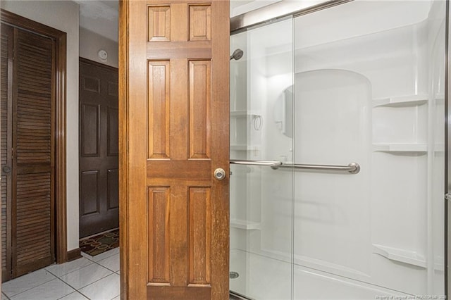 bathroom with a stall shower, a closet, and tile patterned floors