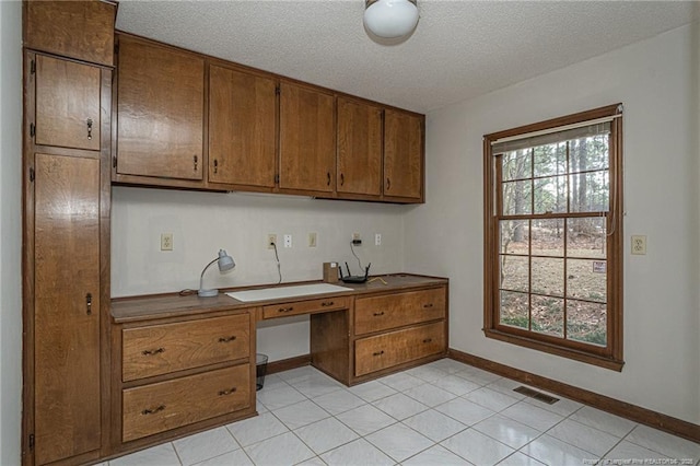 office with built in desk, visible vents, a textured ceiling, and baseboards