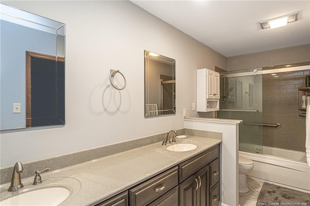 bathroom featuring enclosed tub / shower combo, double vanity, a sink, and toilet