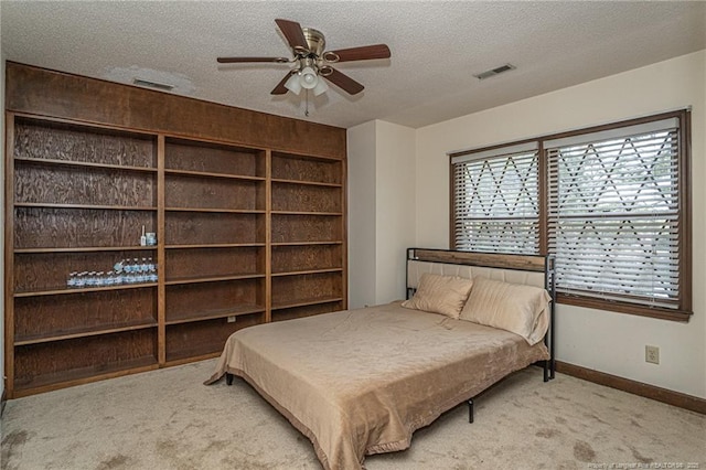 bedroom featuring light carpet, baseboards, visible vents, and a textured ceiling