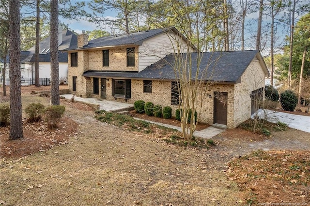 traditional-style house featuring a garage, brick siding, driveway, a chimney, and a patio area