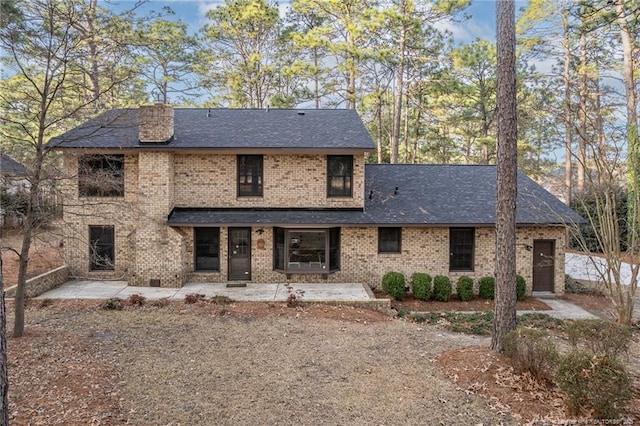 view of front of property with a patio area, a shingled roof, and brick siding