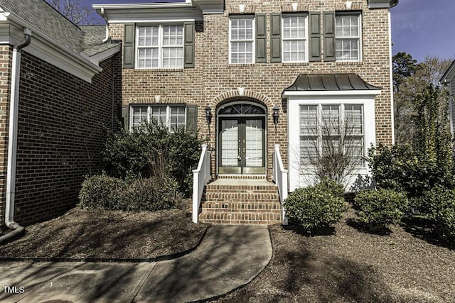 entrance to property featuring french doors and brick siding