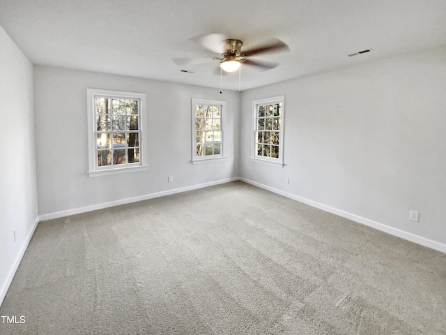 carpeted spare room featuring visible vents, a ceiling fan, and baseboards