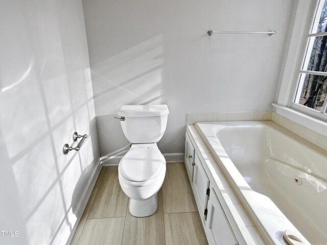 bathroom featuring baseboards, a garden tub, and toilet