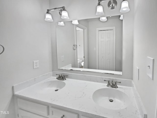 bathroom featuring a closet, a sink, toilet, and double vanity