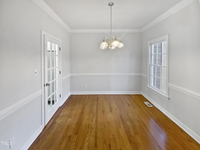 unfurnished dining area with baseboards, ornamental molding, visible vents, and a notable chandelier