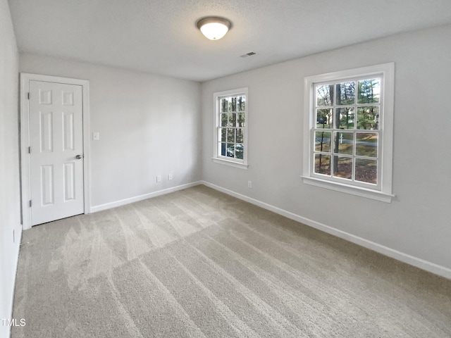 carpeted empty room with visible vents and baseboards