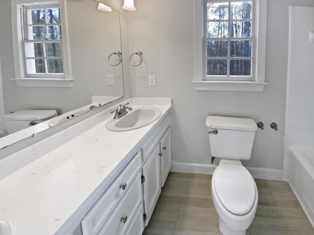 full bathroom with toilet, a bathing tub, vanity, baseboards, and tile patterned floors