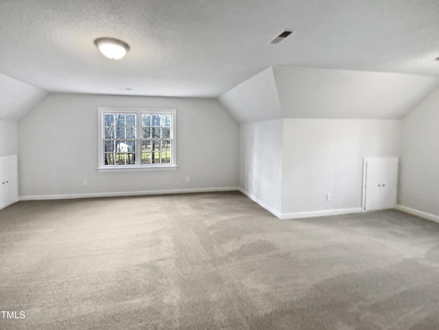 bonus room with visible vents, baseboards, lofted ceiling, carpet, and a textured ceiling