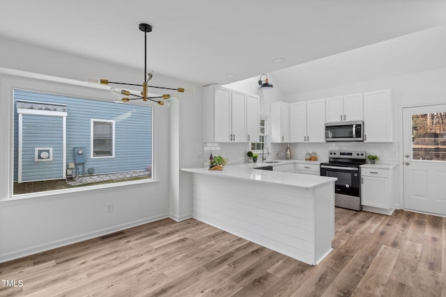 kitchen with white cabinets, decorative backsplash, light wood-style flooring, appliances with stainless steel finishes, and light countertops