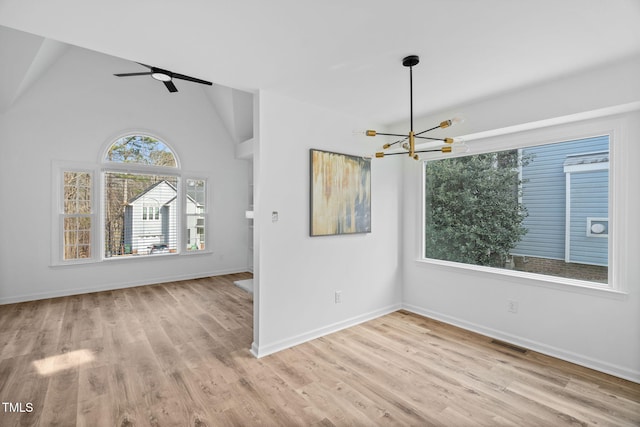 unfurnished room with lofted ceiling, visible vents, an inviting chandelier, wood finished floors, and baseboards