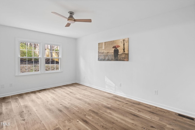 spare room featuring ceiling fan, wood finished floors, visible vents, and baseboards