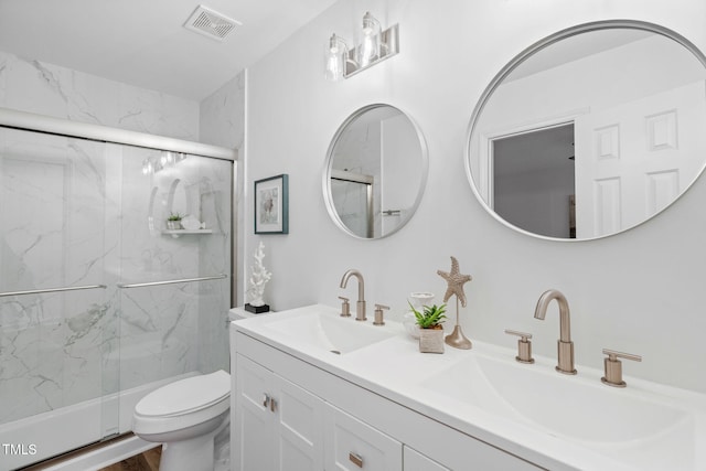 bathroom featuring toilet, a marble finish shower, and a sink