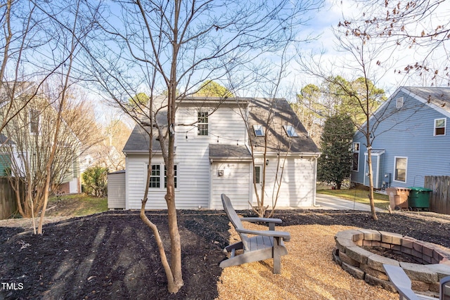 back of house featuring fence, a fire pit, and roof with shingles