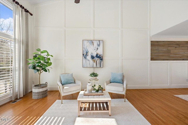 living area with visible vents, a decorative wall, and wood finished floors