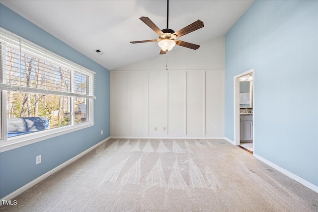 unfurnished bedroom featuring visible vents, light carpet, vaulted ceiling, ensuite bath, and baseboards