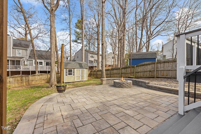 view of patio / terrace featuring a fire pit, a storage shed, an outbuilding, and a fenced backyard