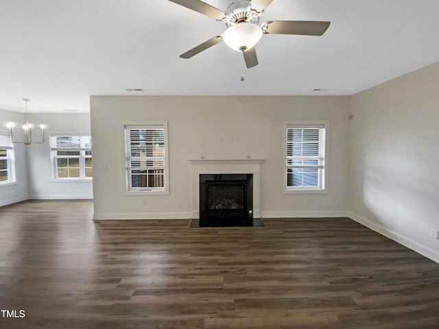 unfurnished living room with ceiling fan with notable chandelier, dark wood-type flooring, a premium fireplace, visible vents, and baseboards