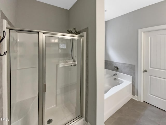 bathroom with a stall shower, tile patterned flooring, and a bath