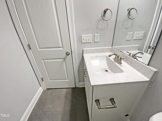 half bathroom with tile patterned floors, baseboards, and vanity