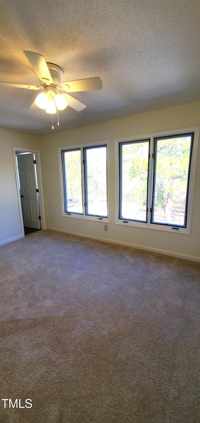 carpeted spare room with ceiling fan, baseboards, and a textured ceiling