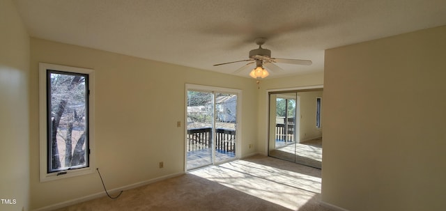 spare room featuring light carpet, ceiling fan, a textured ceiling, and baseboards