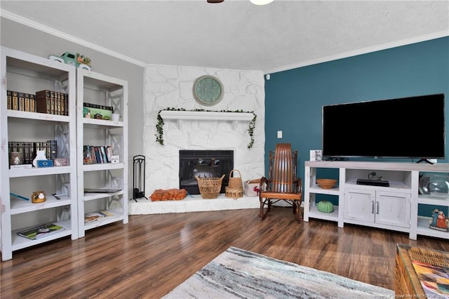 living area featuring a textured ceiling, dark wood finished floors, crown molding, and a stone fireplace