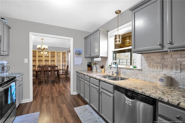 kitchen with appliances with stainless steel finishes, a sink, decorative light fixtures, and gray cabinetry