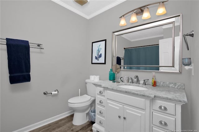 bathroom with crown molding, toilet, vanity, wood finished floors, and baseboards