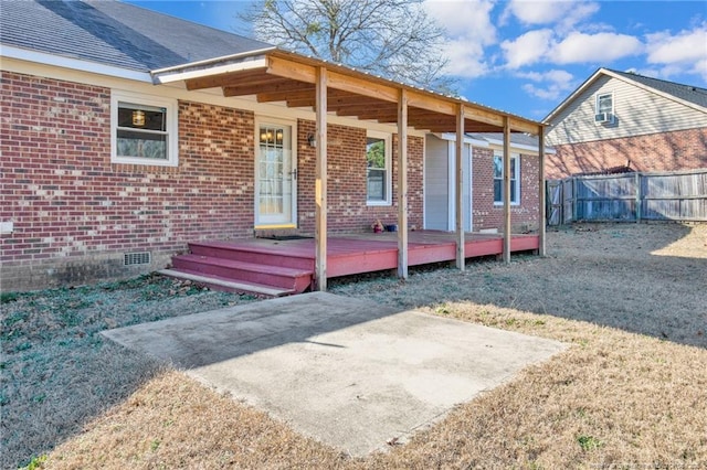 exterior space featuring a deck, brick siding, fence, crawl space, and a lawn