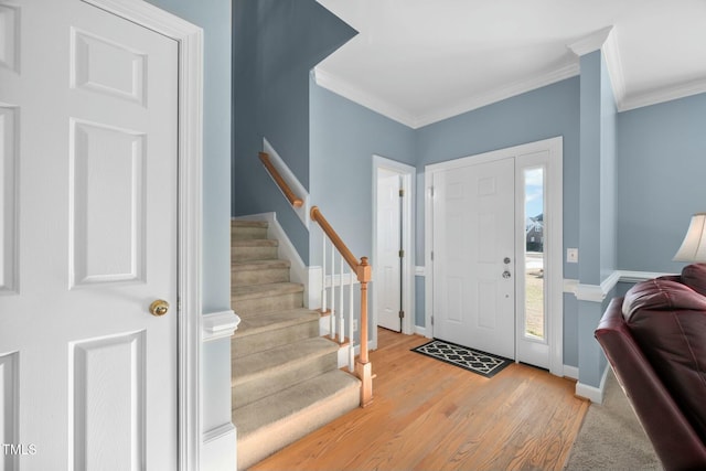 entryway with ornamental molding, light wood-style floors, stairway, and baseboards