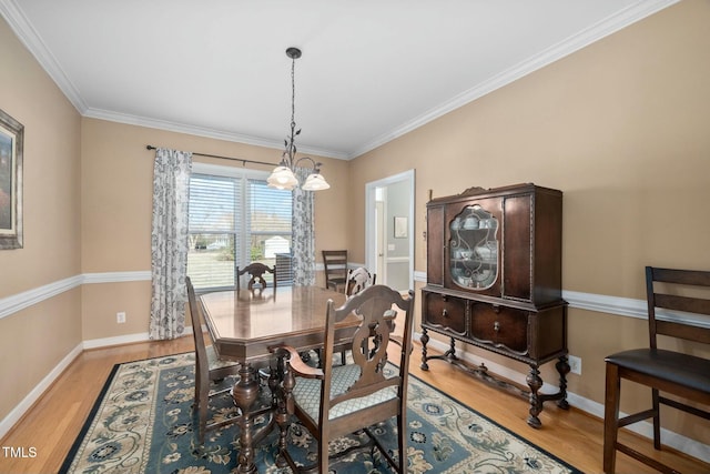 dining room featuring light wood-type flooring, crown molding, and baseboards