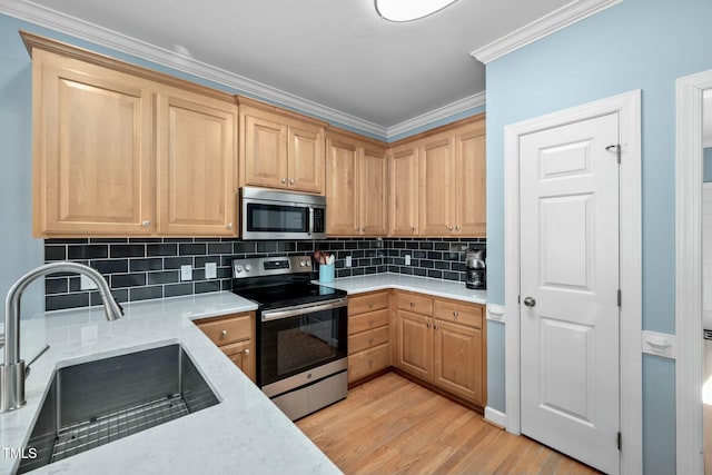 kitchen featuring light stone counters, crown molding, stainless steel appliances, light wood-style floors, and a sink