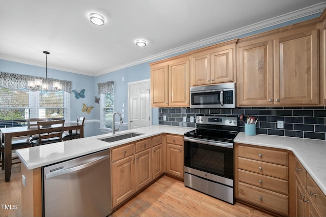 kitchen featuring stainless steel appliances, a peninsula, a sink, light countertops, and decorative light fixtures