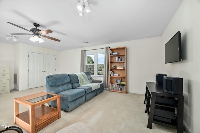 living room with ceiling fan, visible vents, baseboards, and light colored carpet