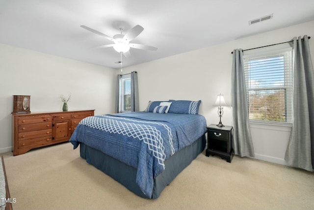 bedroom featuring a ceiling fan, visible vents, light carpet, and baseboards