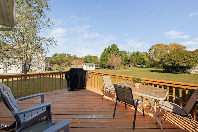 wooden terrace featuring outdoor dining area, a grill, and a lawn