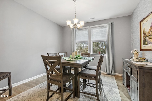 dining space with a notable chandelier, light wood-type flooring, visible vents, and baseboards