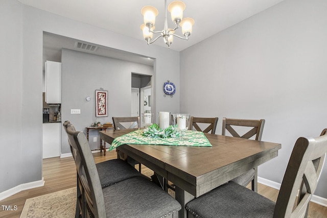 dining area with light wood-type flooring, visible vents, a notable chandelier, and baseboards