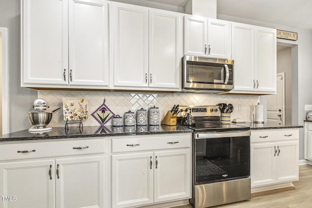 kitchen with white cabinets, appliances with stainless steel finishes, dark stone counters, and backsplash