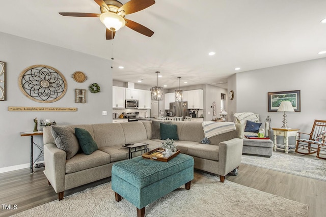 living room with light wood-style flooring, baseboards, a ceiling fan, and recessed lighting