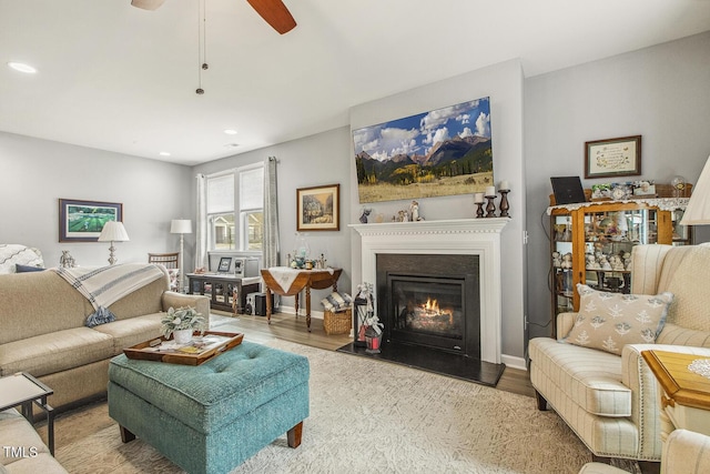 living area featuring a fireplace with flush hearth, baseboards, wood finished floors, and recessed lighting