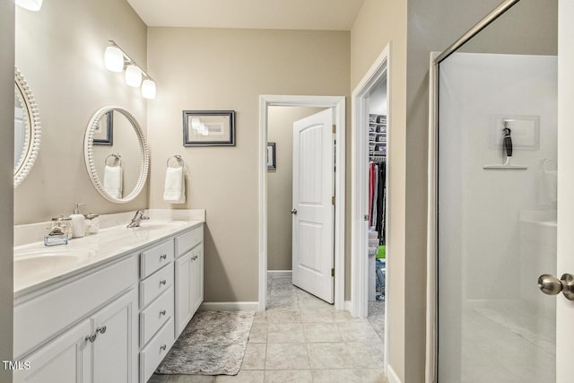 bathroom featuring double vanity, a stall shower, baseboards, a walk in closet, and a sink