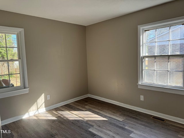 unfurnished room with baseboards, visible vents, and dark wood-style flooring